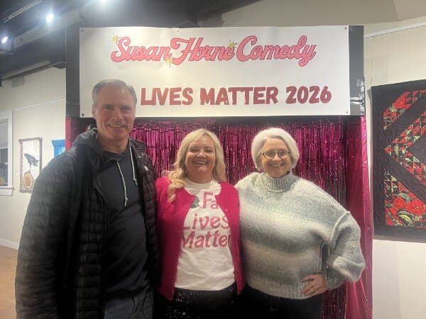 Susan with a couple in front of the pink tinsel photo backdrop