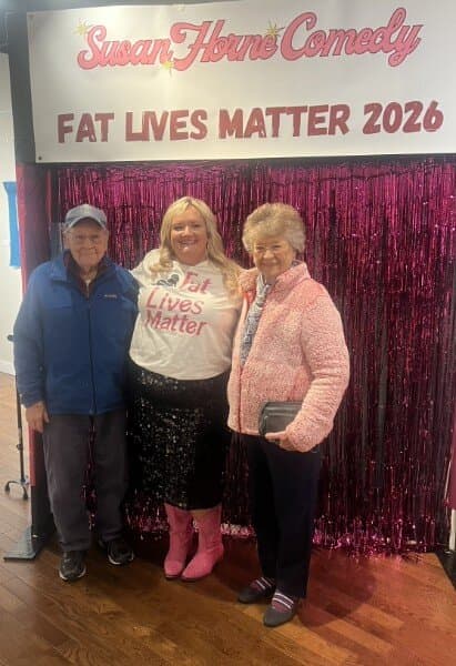 Susan with an older couple at the pink tinsel photo backdrop