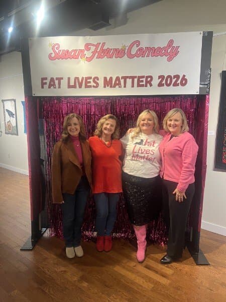Susan with three friends in a group pose at the photo backdrop
